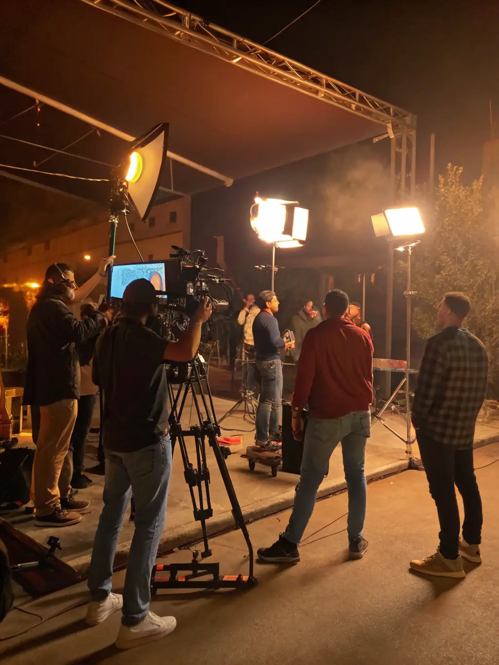 A behind-the-scenes photograph of an audiovisual project being produced by ASSOCIATION EM PROD, featuring a film crew working on set, with actors rehearsing their lines and technicians adjusting equipment.